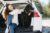 mulher sentada na beira do porta-malas do carro com um cachorro de porte grande marrom
